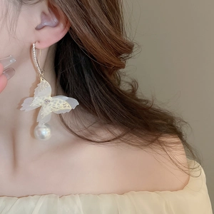 Detail of mesh butterfly earrings with purple crystals and hanging pearl drop