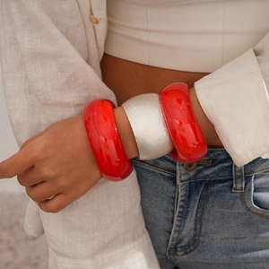 Close-up of three wide bangles with red resin and silver hammered metal texture on model