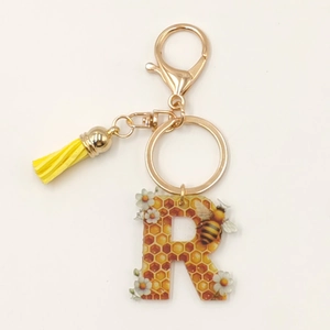 Letter R acrylic keychain with honeycomb bee pattern and yellow tassel detail