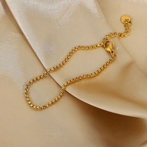 Minimalist 316 stainless steel gold snake chain lying on elegant champagne satin fabric