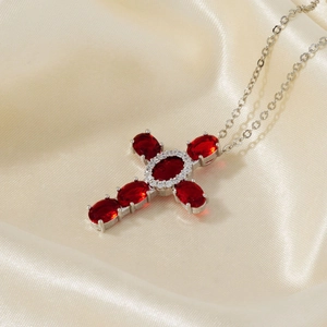 Silver micro-paved cross pendant necklace with red oval gems on beige silk