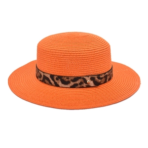 Dettaglio di cappello di paglia arancione con trama intrecciata e nastro leopardato