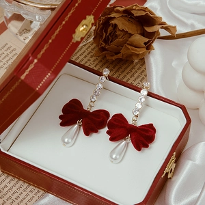 Detail of red velvet bow earrings with rhinestones and white teardrop pearl drop
