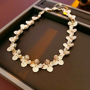 Macro detail of golden petal-shaped metallic necklace texture on jewelry tray