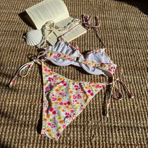 Detailansicht eines floralen Bikini-Sets mit seitlichen Bändern auf sommerlichem Hintergrund