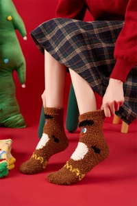 Close-up of thick brown Christmas coral fleece socks with cartoon plush dolls on red background