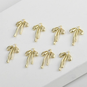 Eight gold bow-shaped 14k plated pendants with small sparkling rhinestones for DIY jewelry