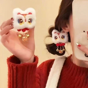 Detail of white fluffy dancing lion hair clip with red embroidery and golden mini bells