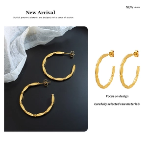 Detailed close-up of golden C-shaped hoop earrings with a polished bamboo texture design