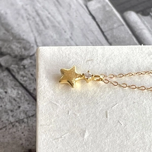 Close-up of golden star pendant necklace with cubic zirconia on white box