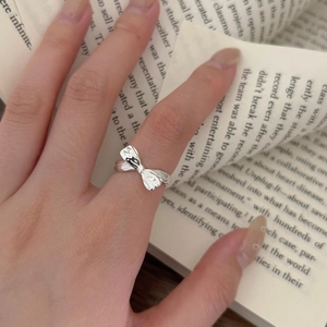 Detail of S925 silver bow ring with vertical stripes worn over an open vintage book