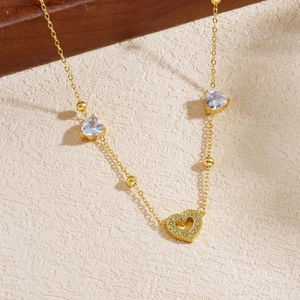Gold heart pendant necklace with clear crystals and pavé stones on a textured surface