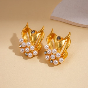 Detailed close-up of golden wing earrings with elegant pearls and sparkling rhinestones
