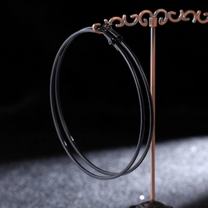 Macro shot of large shiny black hoop earrings hanging on a vintage bronze jewelry stand