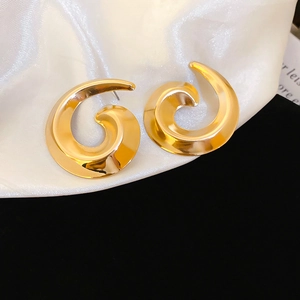 Detailed view of polished golden spiral stud earrings on a silk background
