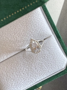 Macro shot of silver teardrop halo ring with split shank in a green velvet box