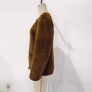 Close-up of brown plush faux shearling jacket with black binding details and round collar