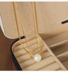 Detail of double-layer gold chain necklace with white pearl pendant in a premium jewelry box