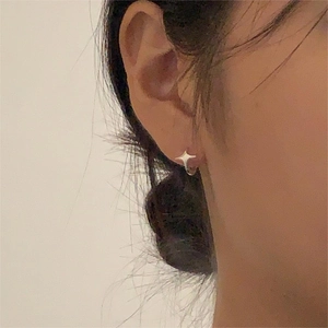 Macro view of minimalist 925 sterling silver four-pointed star stud earring on ear