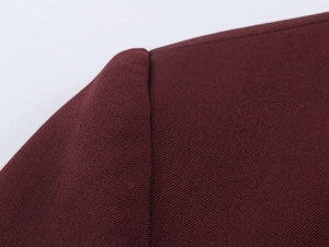 Detail of burgundy woven fabric showing shoulder stitching and vintage metal button