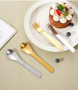 Macro detail of gold and silver stainless steel dessert spoons and forks on a table