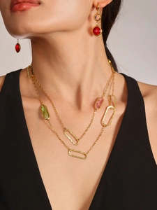 Detail of luxury gold plated necklace and earrings set with red and pink gems