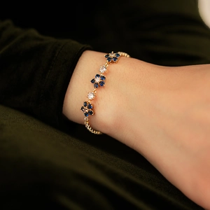 Detail of floral gold bracelet featuring deep blue and white cubic zirconia stones
