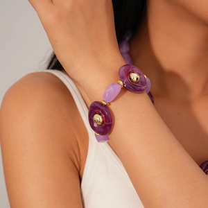 Detail of purple acrylic beads and golden metallic connectors on a female wrist
