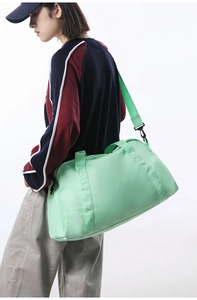 Side view of a large mint green travel duffel bag carried by a female model on white background
