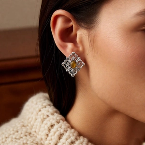 Detail shot of vintage silver rhombic hollow earrings with amber tiger eye stone inlay