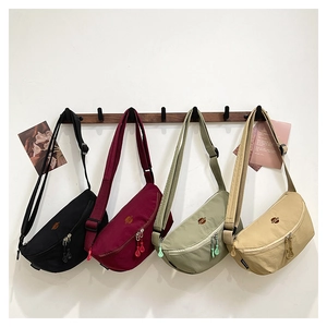 Fila de bolsos bandolera de nailon en negro, granate, verde y caqui sobre ganchos