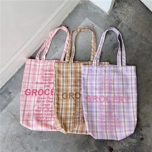 Detailed view of checkered canvas tote bags in pink, brown and purple with grocery print