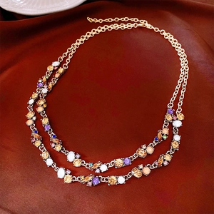 Detail of double-layer gold necklace featuring multi-color gemstones and vintage chains