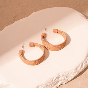 Detailed view of brown layered C-shape earrings on white stone display props