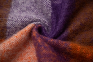 Macro view of purple and orange plaid boucle knit fabric showing soft fuzzy texture