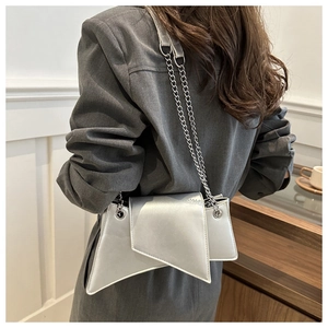 Détail d'un sac à bandoulière asymétrique en cuir argenté avec une chaîne élégante