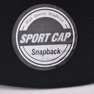 Close-up of black snapback hat showing high-quality twill fabric and round visor sticker