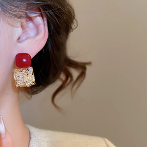 Vue détaillée des boucles d'oreilles avec perle rouge et zircon portées par un mannequin