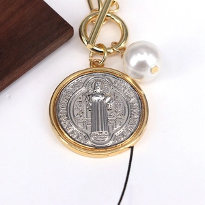 Detail of a vintage coin pendant with Virgin Mary engraving and a white pearl accent