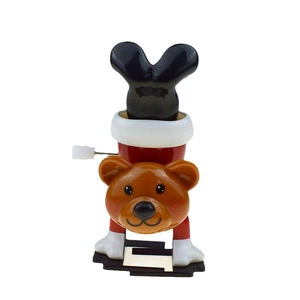Detail of a brown clockwork bear toy standing upside down with a red body and white trim