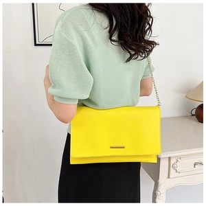 Detail showing bright yellow PU leather envelope bag with golden chain strap on a model