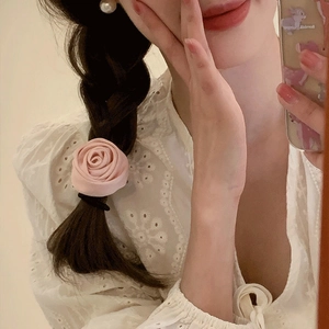 Détail d'un chouchou rose en forme de fleur porté en tresse pour un style romantique doux