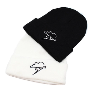 Close-up of cloud and lightning embroidery on thick knit beanies in black and white