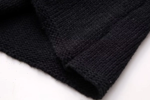 Detailed close-up of the black knit fabric texture and fine stitching on the sleeve cuff