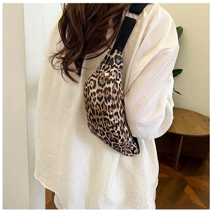 Close-up of leopard print crossbody bag with black adjustable strap on a model