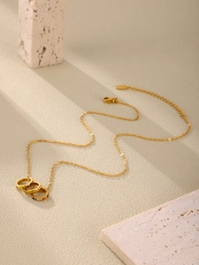 Close-up of triple ring gold necklace with rainbow zircons and With Love engraving