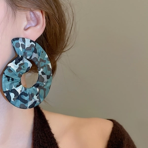 Detailed side view of large fabric hoop earrings with teal camouflage print on model