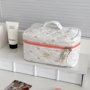 Détails de la trousse de maquillage blanche matelassée avec nœuds roses et ruban