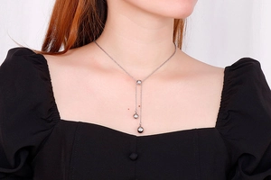 Y-shaped silver stainless steel bead necklace displayed on a model in black top