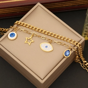Detail of gold double-layered bracelet featuring evil eye, star, and blue drop charms